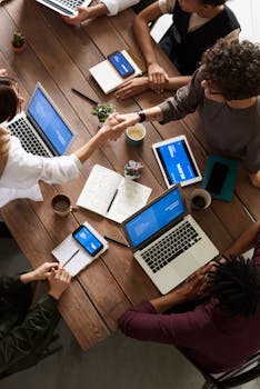A diverse group of professionals brainstorming in a modern workspace with laptops and notebooks.